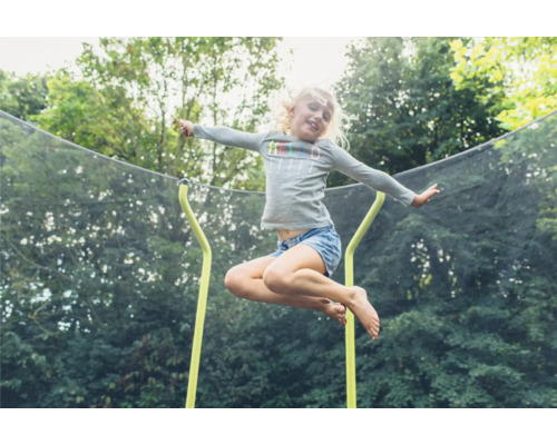 Ein Mädchen springt auf einem Gartentrampolin mit Sicherheitsnetz.