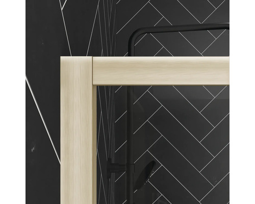 Detailaufnahme einer Duschkabine mit hellen Rahmen vor einer Wand mit Fischgrätenmuster.