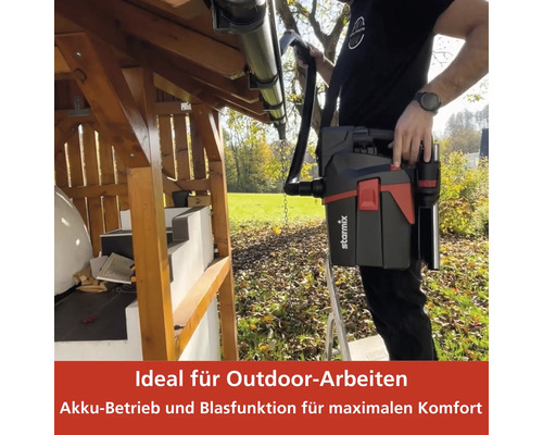 Eine Person reinigt mit einem tragbaren Staubsauger eine Dachrinne im Außenbereich.