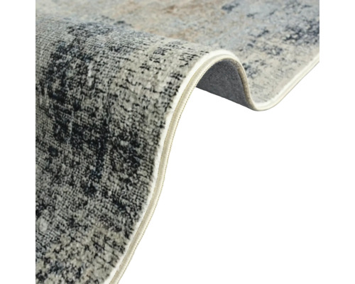 Detailansicht eines Teppichs mit abstraktem Muster und gekettelten Kanten.