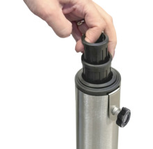 Eine Hand setzt eine schwarze Reduzierhülse auf einen Metallständer für einen Sonnenschirm.