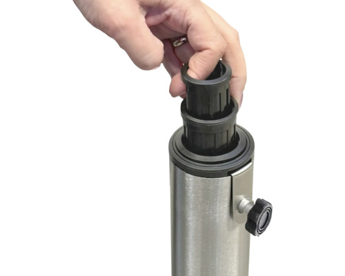 Eine Hand setzt eine schwarze Reduzierhülse auf einen Metallständer für einen Sonnenschirm.