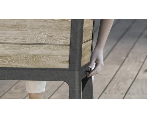 Detailansicht eines Hochbeets aus Holz und Metall mit einer Person, die einen Knopf bedient