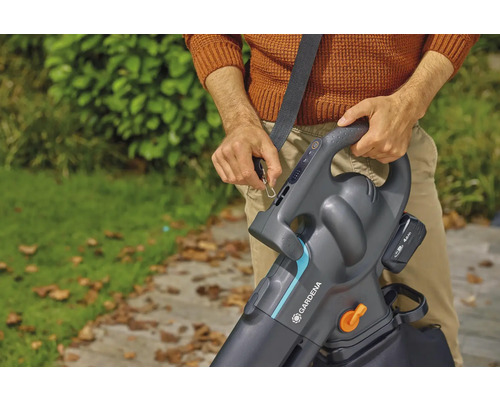 Eine Person befestigt einen Gardena Akku-Laubsauger mit Schultergurt