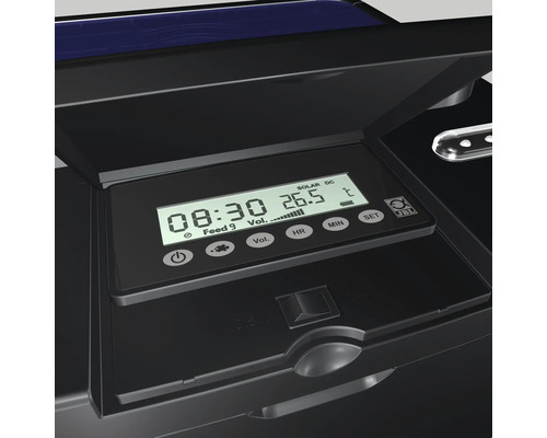 Detailansicht eines schwarzen Futterautomaten mit digitalem Display, das die Uhrzeit und Temperatur anzeigt