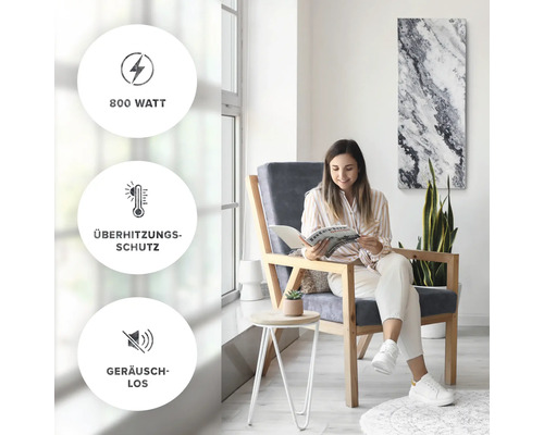 Frau liest Zeitschrift in einem hellen, modernen Raum mit einem Heizpaneel an der Wand. Die Symbole zeigen 800 Watt Leistung, Überhitzungsschutz und geräuschlosen Betrieb.
