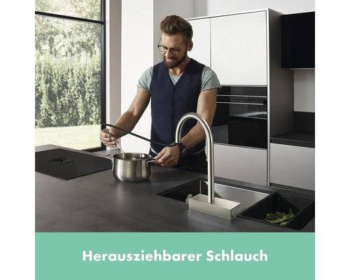 Mann befüllt Topf mit ausziehbarer Küchenarmatur in moderner Küche