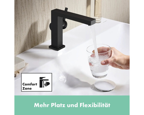 Schwarzer Wasserhahn am Waschbecken mit Wasser, das in ein Glas fließt