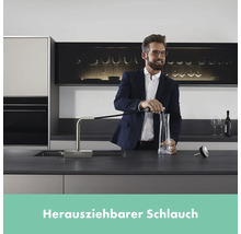 Mann füllt Wasser in eine Karaffe mit einem Wasserhahn mit herausziehbarem Schlauch in einer modernen Küche