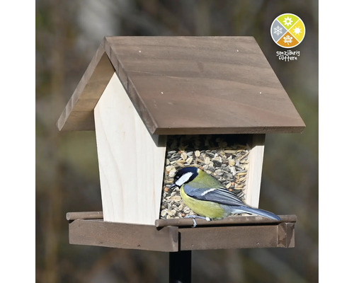 Vogelhäuschen aus Holz mit einer Kohlmeise und dem Symbol für ganzjährige Fütterung.