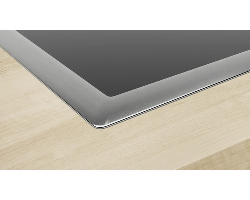 Detailansicht eines Kochfelds mit Edelstahlrahmen in einer Holzarbeitsplatte