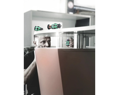 Ein Mann befestigt mit einem Schraubendreher ein Möbelstück.