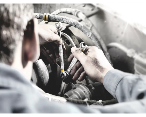 Ein Mann arbeitet mit zwei Maulschlüsseln an einem Motor.