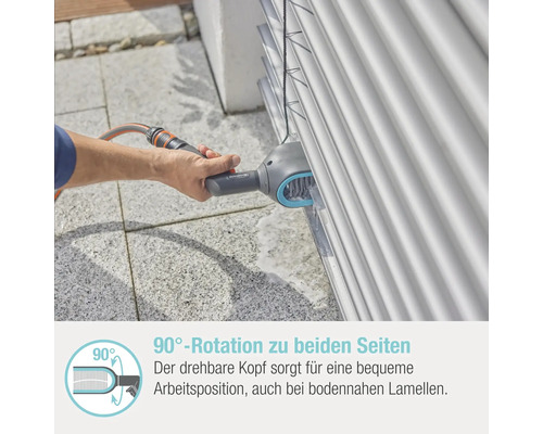 Eine Person reinigt Jalousien mit einer Bürste und einem Wasserschlauch.
