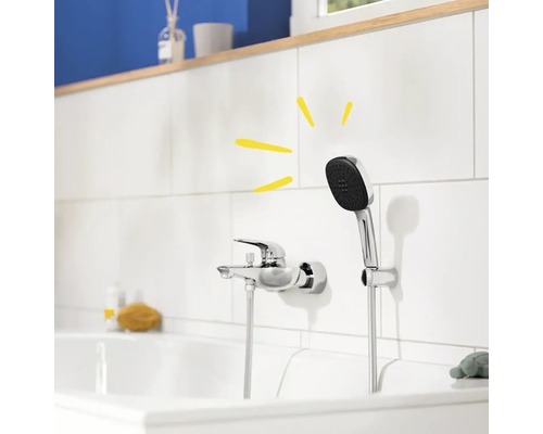 Aufnahme eines Badezimmers mit einer Armatur und einer Handbrause an einer weißen gefliesten Wand