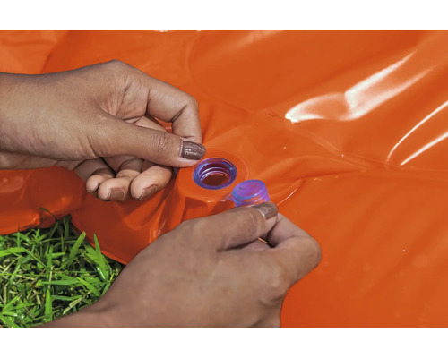 Eine Person verschließt ein orangefarbenes aufblasbares Planschbecken mit einem blauen Verschlussstopfen.