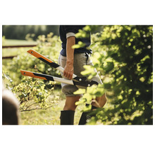 Eine Person hält eine Getriebeastschere mit Hebelwirkung in einem Garten