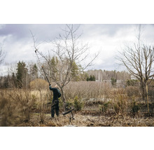 Eine Person beschneidet einen Baum mit einer Astschere im Garten.