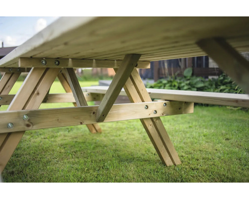 Detailansicht eines Holztisches mit Bänken im Garten.