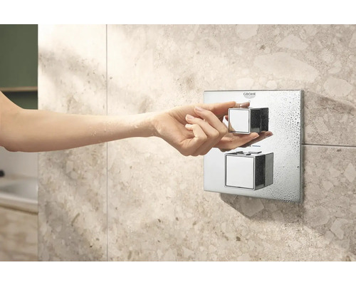Nahaufnahme einer Hand, die einen Duschthermostat von Grohe bedient