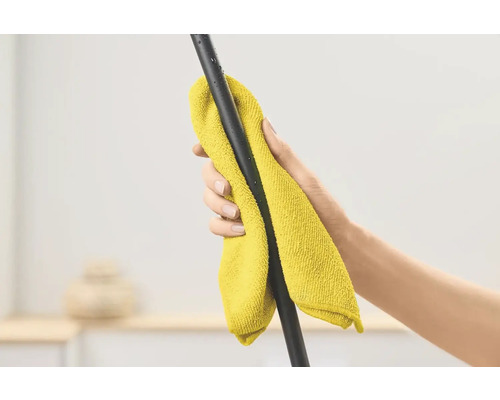 Eine Hand wischt eine schwarze Stange mit einem gelben Mikrofasertuch ab