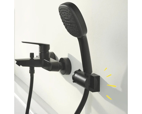 Schwarze Badewannenarmatur mit Handbrause und Brauseschlauch an der Wand montiert.