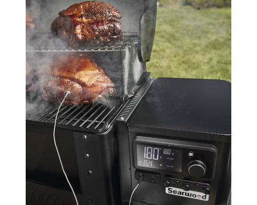 Detailansicht eines Searwood Grills mit Fleisch auf dem Rost und einem Temperaturfühler zur Überwachung des Garzustands.