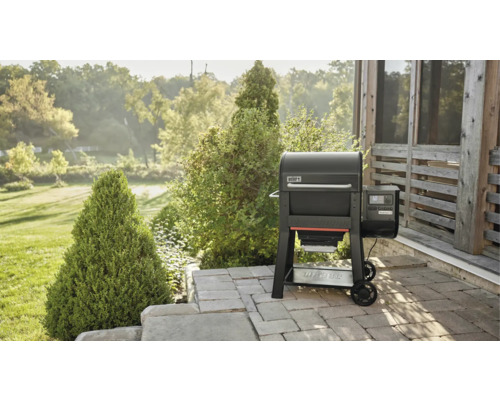 Weber Pelletgrill auf einer Terrasse mit Garten im Hintergrund.