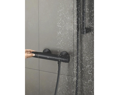 Aufnahme einer Duscharmatur mit Thermostat und einer Hand, die den Temperaturregler betätigt.