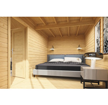 Innenansicht eines Holzhauses mit Bett, Nachttisch und geöffneter Tür