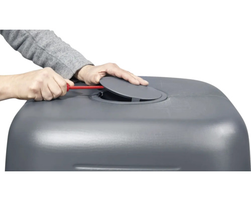 Person hantiert mit Schraubenzieher an grauer Regentonne