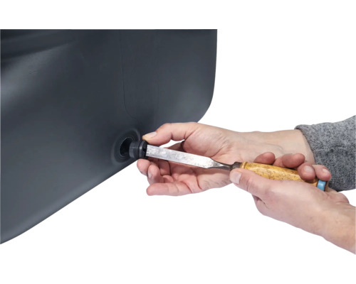 Eine Person, die mit einem Stecheisen an einem schwarzen Behälter arbeitet