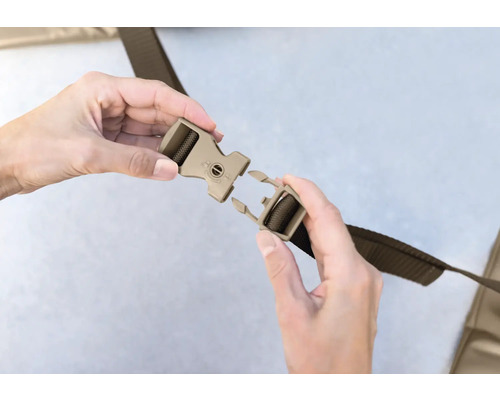 Eine Person schliesst einen Gurt mit einem Klickverschluss.