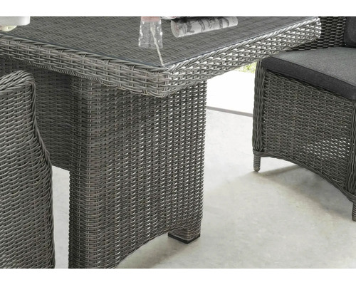 Nahaufnahme eines Rattantisches mit Glasplatte und Rattanstuhl mit Kissen, ideal für den Garten