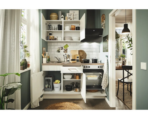 Komplette Küche mit Hängeschränken, Spüle, Kochfeld und Backofen in einem hellen Raum.