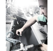 Ein Mann repariert eine Maschine mit einem Schraubenzieher.