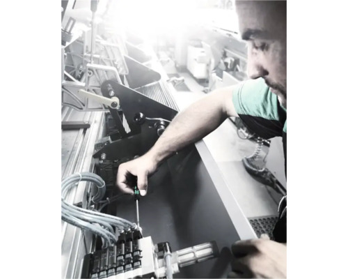 Ein Mann repariert eine Maschine mit einem Schraubenzieher.