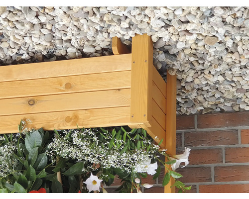 Holzpflanzkasten mit blühenden Pflanzen unter einem Dach aus Kies