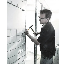 Handwerker stemmt Fliesen mit Hammer und Meißel ab.