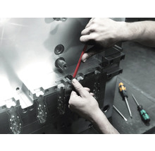 Ein Arbeiter führt mit einem Schraubendreher Wartungsarbeiten an einem Metallwerkzeug durch.