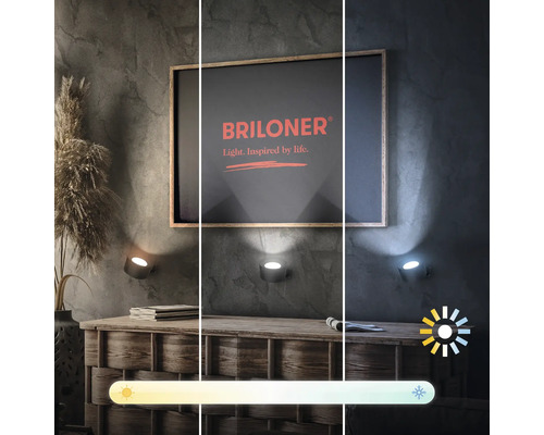 Drei Wandleuchten mit unterschiedlicher Lichtfarbe über einer Kommode und einem gerahmten Bild mit dem Briloner Logo
