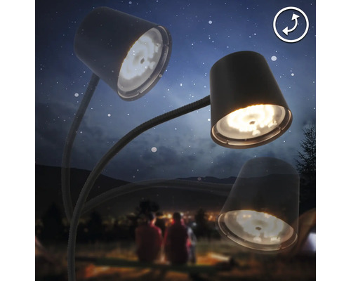 Dreiarmige Schreibtischlampe vor einem Hintergrund mit Personen und Zelten