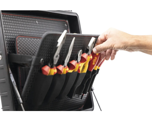 Werkzeugkoffer mit diversen Zangen und Werkzeugen, die in schwarzen Halterungen aufbewahrt werden. Eine Hand greift nach einer Zange der Marke Wiha.