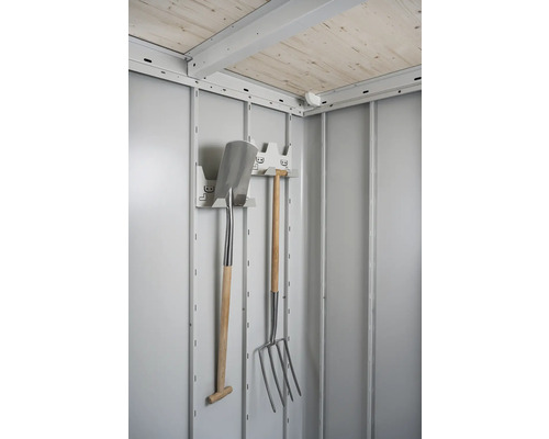 Innenansicht eines Geräteschuppens mit Gartengeräten wie Spaten und Mistgabel an einer Halterung
