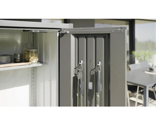 Geöffneter Gartenschrank mit Regalböden und Grillutensilien an der Tür