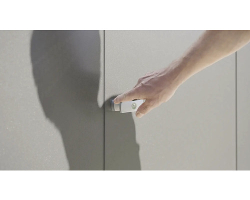 Eine Hand betätigt einen Schrankschnapper an einer Schranktür.