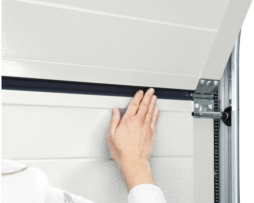 Detailaufnahme einer Hand, die eine Garagentordichtung anbringt