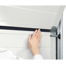 Detailansicht eines Garagentors mit einer Person, die eine Dichtung anbringt.