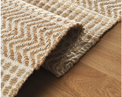 Detailansicht eines hellen Teppichs mit Zickzackmuster auf Holzboden