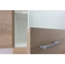 Detailaufnahme eines Möbels mit Holzoberfläche, Glasplatte und Metallgriff